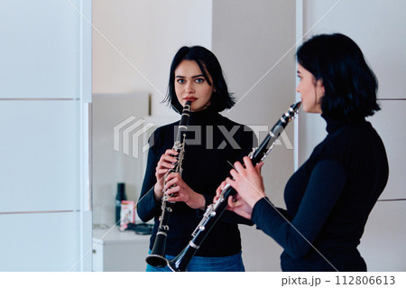 Graceful Brunette Musician Posing with Clarinet on White Background 112806613