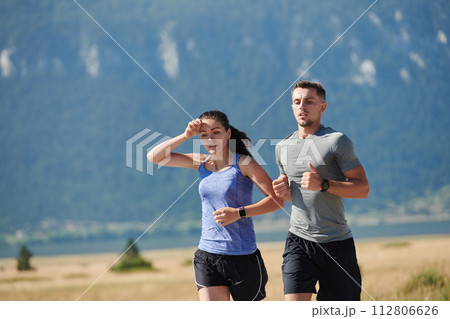 Energized by the beauty of nature, a couple powers through their morning run, their bodies and spirits invigorated. 112806626