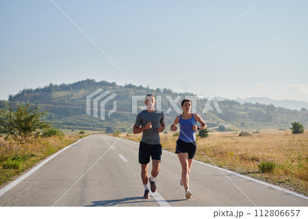 Energized by the beauty of nature, a couple powers through their morning run, their bodies and spirits invigorated. 112806657