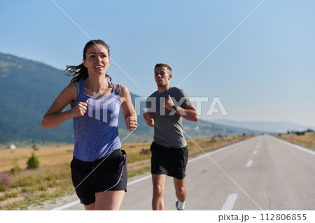 Energized by the beauty of nature, a couple powers through their morning run, their bodies and spirits invigorated. 112806855