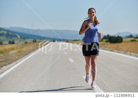 A determined woman athlete trains for success in the morning sun. A determined woman athlete trains for success in the morning sun. 112806911