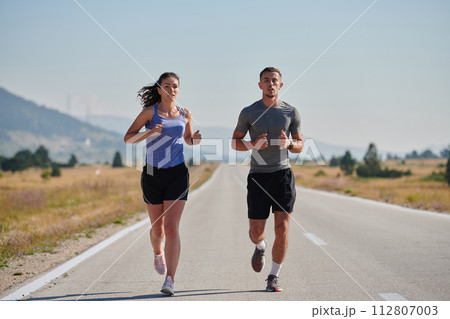 Energized by the beauty of nature, a couple powers through their morning run, their bodies and spirits invigorated. 112807003