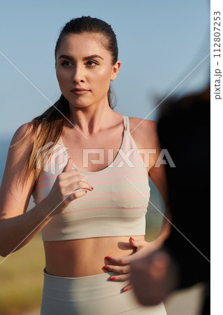 A determined woman athlete trains for success in the morning sun. A determined woman athlete trains for success in the morning sun. 112807253