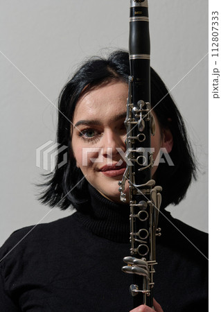 Graceful Brunette Musician Posing with Clarinet on White Background 112807333