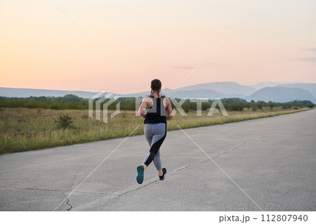 Solo Stride: Determined Athlete Woman Embarks on Fitness Journey for Marathon Preparation. 112807940