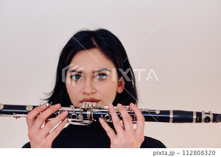 Graceful Brunette Musician Posing with Clarinet on White Background 112808320