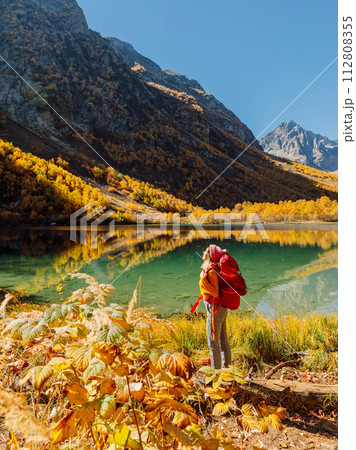 Woman hiker enjoying at lake in mountains. Lake and hiker lady with backpack Woman hiker enjoying at lake in mountains. Lake and hiker lady with backpack 112808355