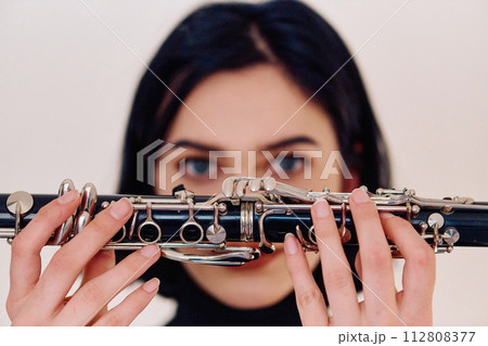 Graceful Brunette Musician Posing with Clarinet on White Background 112808377