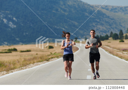 Energized by the beauty of nature, a couple powers through their morning run, their bodies and spirits invigorated. 112808448
