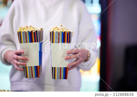 A vendor stands outside the cinema, holding freshly popped popcorn to sell to moviegoers before they enter the theater 112808638