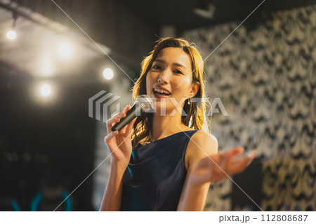 歌を熱唱する女性　 112808687