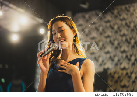 歌を熱唱する女性　 112808689
