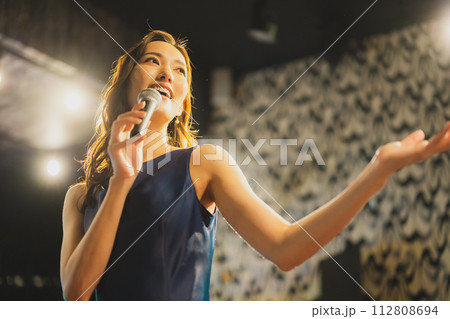 歌を熱唱する女性　 112808694