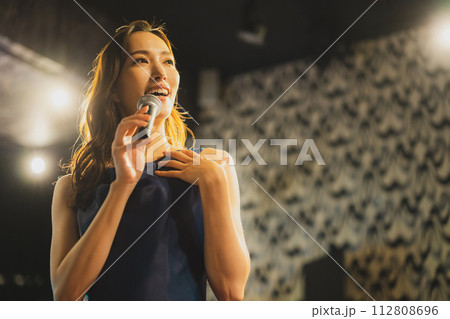 歌を熱唱する女性　 112808696