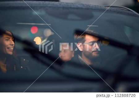 In the nighttime hours, a happy family enjoys playful moments together inside a car as they journey on a nocturnal road trip, illuminated by the glow of headlights and filled with laughter and joy 112808720