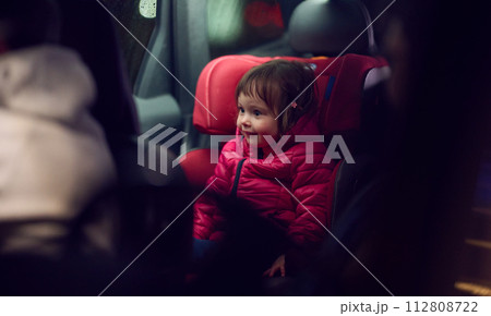 A young girl sits comfortably in a modern car seat, secured and ready for a family adventure on the road. A young girl sits comfortably in a modern car seat, secured and ready for a family adventure on the road. 112808722