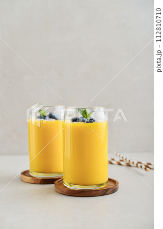 Refreshing and healthy mango smoothie with coconut flakes and fresh blueberries Refreshing and healthy mango smoothie with coconut flakes and fresh blueberries 112810710