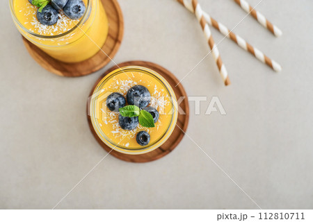 Refreshing and healthy mango smoothie with coconut flakes and fresh blueberries Refreshing and healthy mango smoothie with coconut flakes and fresh blueberries 112810711