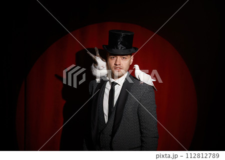 Elegant mysterious illusionist showing tricks with dove and rabbit 112812789