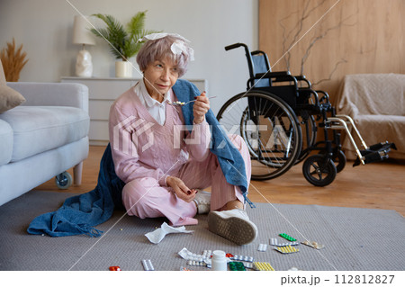 Senior woman with dementia mental disorder eating pills scattered on floor 112812827
