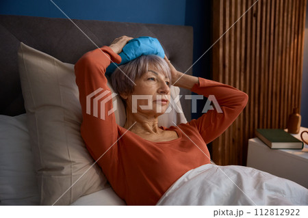 Senior woman with headache feeling upset unhappy lying in bed Senior woman with headache feeling upset unhappy lying in bed 112812922