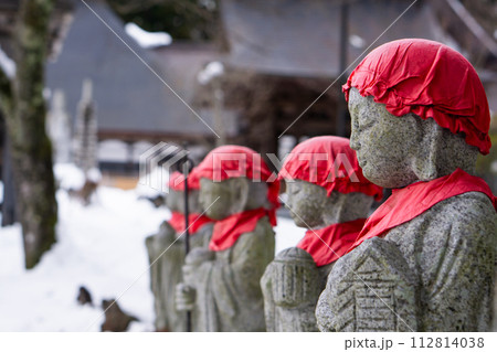 Japanese Jizo statues with red caps in a winter landscape. Japanese Jizo statues with red caps in a winter landscape. 112814038