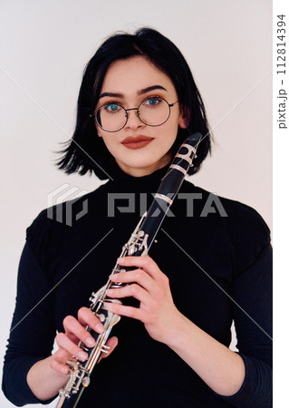 Graceful Brunette Musician Posing with Clarinet on White Background 112814394