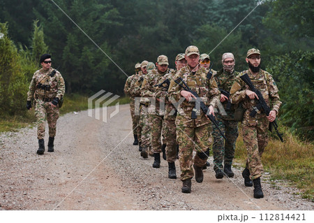 An elite military unit, led by a major, confidently parades through dense forest, showcasing precision, discipline, and readiness for high-risk operations An elite military unit, led by a major, confidently parades through dense forest, showcasing precision, discipline, and readiness for high-risk operations 112814421