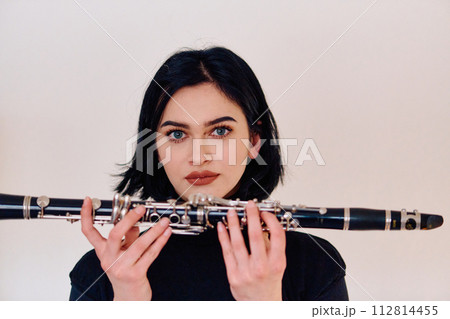 Graceful Brunette Musician Posing with Clarinet on White Background Graceful Brunette Musician Posing with Clarinet on White Background 112814455