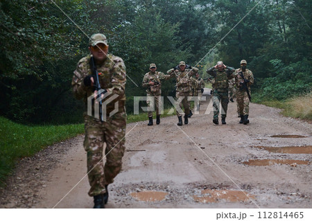 A group of elite soldiers leads captives through a military camp, showcasing a tense atmosphere of detention and security operations 112814465