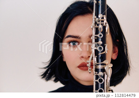 Graceful Brunette Musician Posing with Clarinet on White Background 112814479