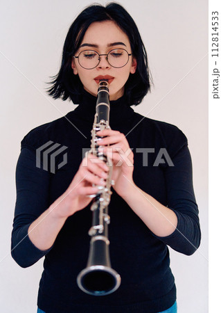 Graceful Brunette Musician Posing with Clarinet on White Background 112814533