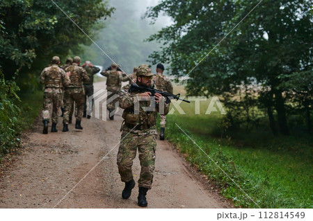 A group of elite soldiers leads captives through a military camp, showcasing a tense atmosphere of detention and security operations 112814549