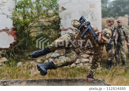 A highly trained elite military unit, clad in camouflage, skillfully navigates through perilous forest terrain, overcoming obstacles and executing a precise and covert mission A highly trained elite military unit, clad in camouflage, skillfully navigates through perilous forest terrain, overcoming obstacles and executing a precise and covert mission 112814880