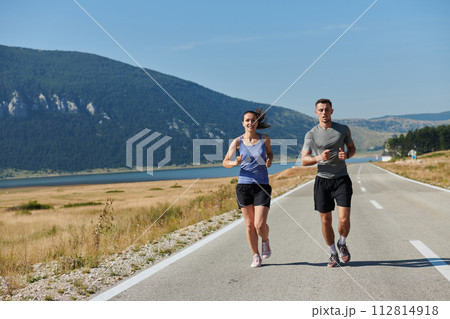 Energized by the beauty of nature, a couple powers through their morning run, their bodies and spirits invigorated. Energized by the beauty of nature, a couple powers through their morning run, their bodies and spirits invigorated. 112814918