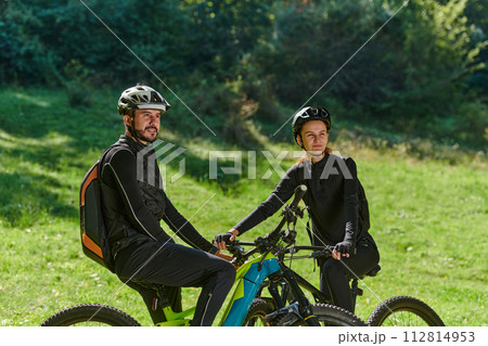 A sweet couple, equipped with bicycles and engrossed in coordinating their journey, checks their GPS mobile and watches while planning scenic routes in the park, seamlessly blending technology and A sweet couple, equipped with bicycles and engrossed in coordinating their journey, checks their GPS mobile and watches while planning scenic routes in the park, seamlessly blending technology and 112814953
