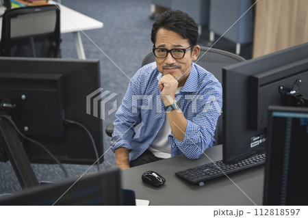 PCに囲まれたカメラ目線で笑顔の50代男性 112818597