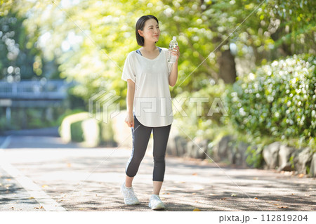 ペットボトルの水を飲むスポーツウエアの若い女性 112819204