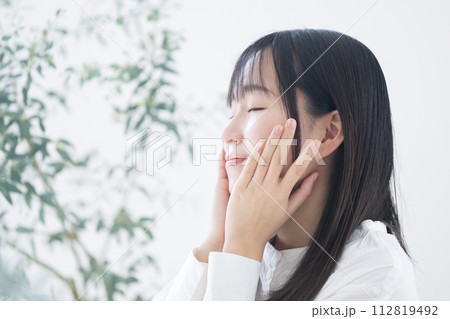頬や肌を両手で触れてスキンケアを気にする若いアジア人(日本人)女性の美容ビューティーイメージ 頬や肌を両手で触れてスキンケアを気にする若いアジア人(日本人)女性の美容ビューティーイメージ 112819492
