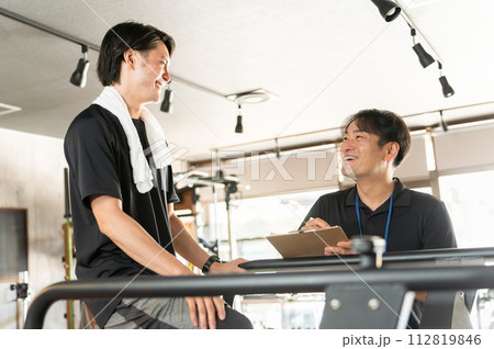 スポーツジムでパーソナルトレーニングを受ける男性とインストラクター・トレーナー 112819846