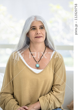 Thoughtful senior Hispanic woman sitting on home couch Thoughtful senior Hispanic woman sitting on home couch 112820758