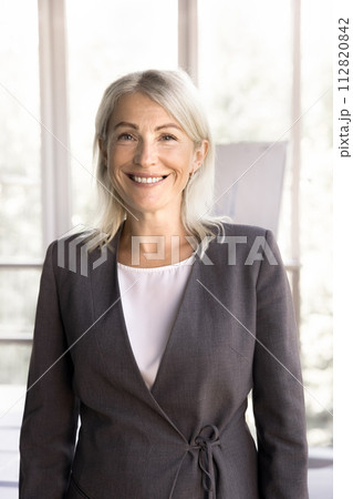Mature female employee smile looks at camera posing at workplace 112820842