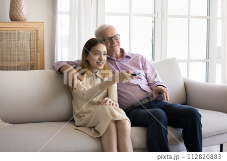 Pre-teen girl spend leisure with older grandfather watching together TV 112820883
