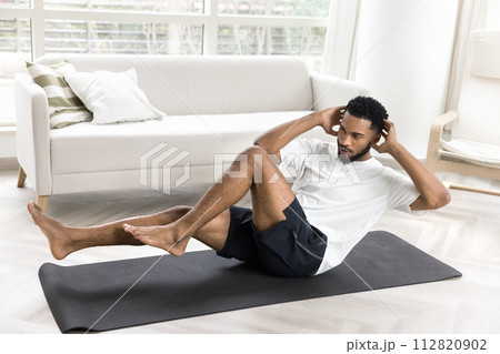 Focused young African athlete guy twisting body in boat pose 112820902