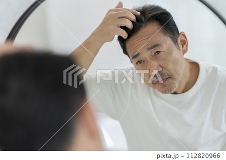 鏡を見ながら髪を気にする50代の男性 鏡を見ながら髪を気にする50代の男性 112820966