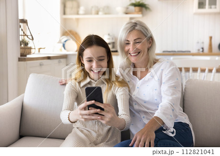Happy mom with pre-teen daughter makes video call use smartphone 112821041