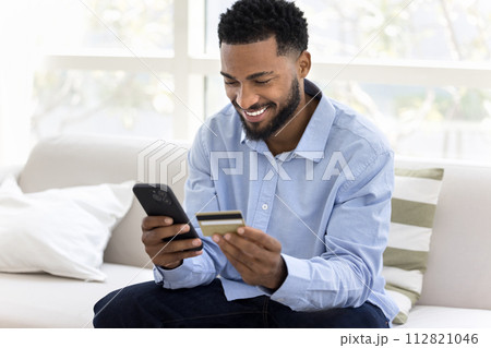 Cheerful young African customer man enjoying online shopping 112821046