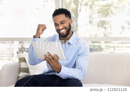 Cheerful overjoyed young African woman celebrating triumph Cheerful overjoyed young African woman celebrating triumph 112821128