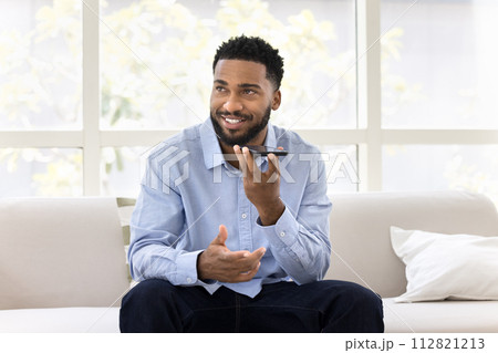Positive handsome young African business man talking on speaker 112821213
