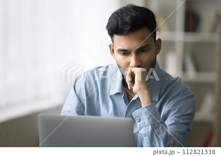 Serious man looks at laptop screen think over business concerns Serious man looks at laptop screen think over business concerns 112821338